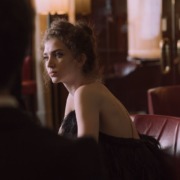 pexels-photo-5378984-5378984 A young woman in a sophisticated black evening dress, sitting in a stylish restaurant setting.